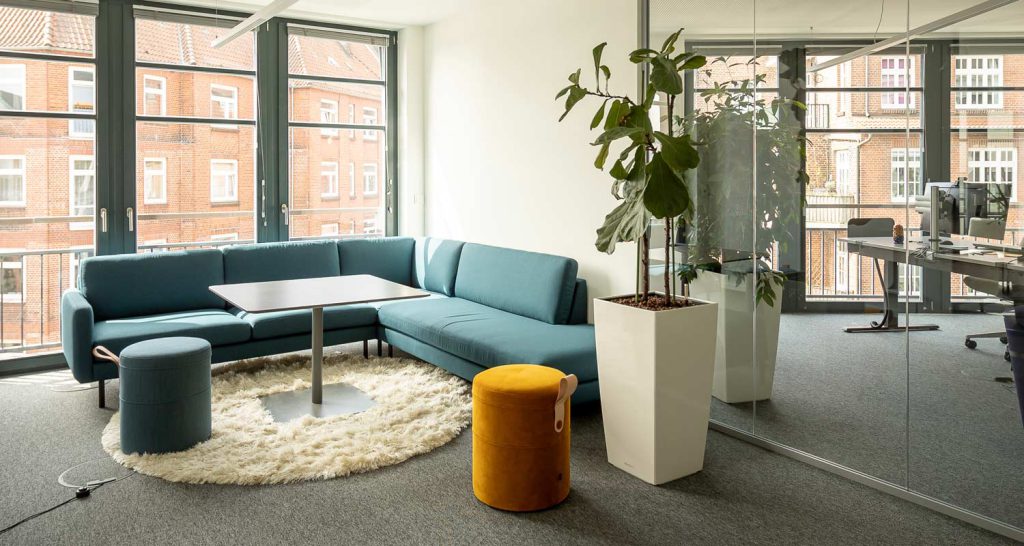 Ein Büro im Zeichen von hybridem Arbeiten: Neben den Tischen ist eine gemütliche Sitzecke mit Sofa eingerichtet.